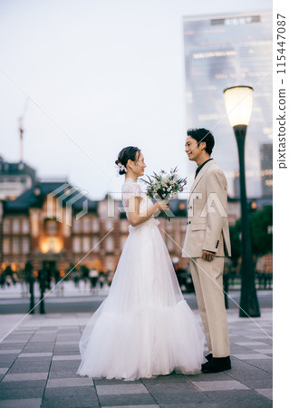 Bride and groom facing each other in front of Tokyo Station 115447087