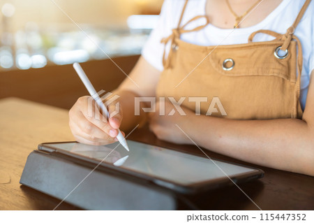 Close-up of asian freelance people business female wearing glasses stylish hipste Draw or taking note on digital tablet with electronic pen for browsing internet, chatting and blogging in coffee shop. Close-up of asian freelance people business female wearing glasses stylish hipste Draw or taking note on digital tablet with electronic pen for browsing internet, chatting and blogging in coffee shop. 115447352