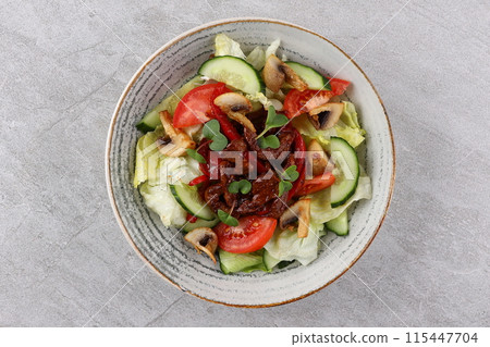 Asian beef salad with vegetables and nuts in a white bowl on a dark background. Asian food concept. Asian beef salad with vegetables and nuts in a white bowl on a dark background. Asian food concept. 115447704