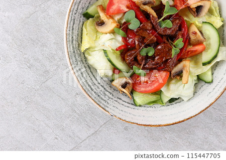 Asian beef salad with vegetables and nuts in a white bowl on a dark background. Asian food concept. 115447705