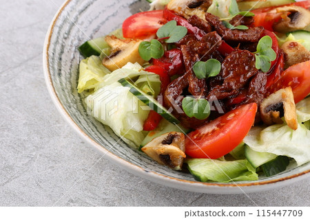 Asian beef salad with vegetables and nuts in a white bowl on a dark background. Asian food concept. 115447709