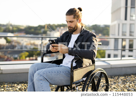 Young man in wheelchair using smartphone on rooftop Young man in wheelchair using smartphone on rooftop 115448053