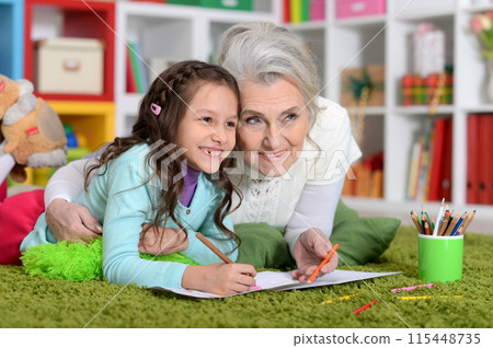 Portrait of grandmother with granddaughter drawing at home  115448735