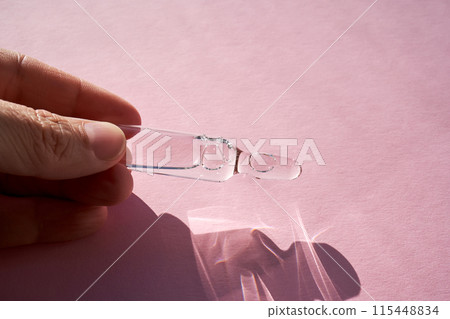 Ampoule for injection with medicines on a pink background in hand. 115448834