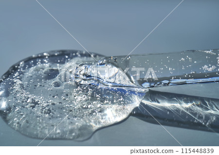 Pipette with serum shimmering in the sun on a blue background. 115448839