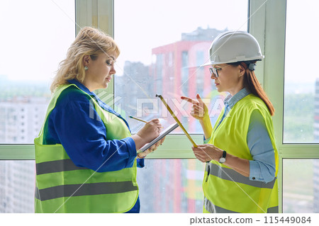 Two female industrial workers taking measurements of windows for decoration 115449084