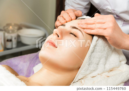 Cosmetologist applying sheet mask on woman's face in beauty salon. Cosmetologist applying sheet mask on woman's face in beauty salon. 115449760