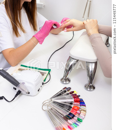 Cosmetologist applying sheet mask on woman's face in beauty salon. Cosmetologist applying sheet mask on woman's face in beauty salon. 115449777