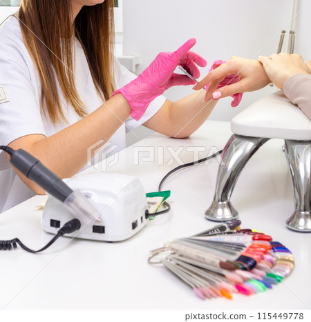 Cosmetologist applying sheet mask on woman's face in beauty salon. Cosmetologist applying sheet mask on woman's face in beauty salon. 115449778