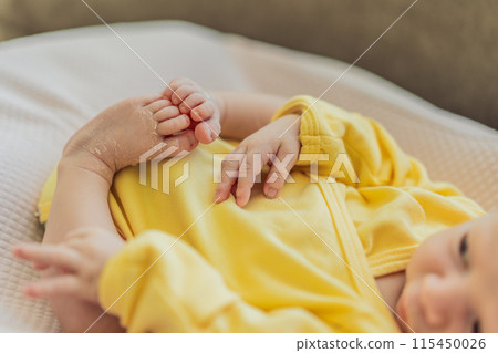 The newborn's skin is peeling. Mom uses skin products and massages to care for and soothe the baby's delicate skin, ensuring comfort and promoting healthy skin 115450026