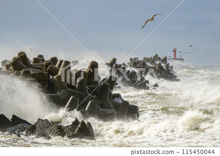Hurricane storm at sea, high waves crashing against the concrete breakwaters of the port 115450044