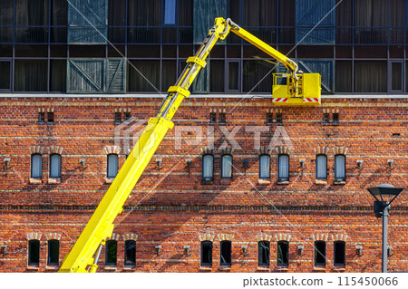 Facade maintenance works of a historic house using a telescopic boom lift with a basket 115450066
