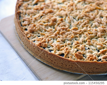 Tart is a round cake with chocolate on a metal mold on a wooden board on a white table background. Homemade cakes, bakery, rustic cuisine, farm products Tart is a round cake with chocolate on a metal mold on a wooden board on a white table background. Homemade cakes, bakery, rustic cuisine, farm products 115450295