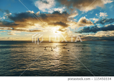 A group of people are enjoying a sunset swim in the ocean together A group of people are enjoying a sunset swim in the ocean together 115450334