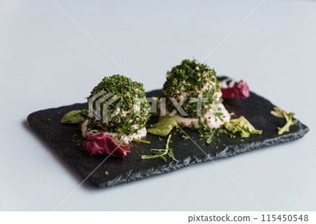 Cheese balls with herbs on a black board on a white background 115450548