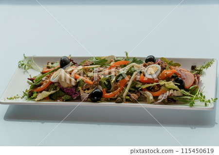 Salad with cabbage, cucumber, egg, onion, tuna and olive oil on a white saucer on a white background Salad with cabbage, cucumber, egg, onion, tuna and olive oil on a white saucer on a white background 115450619