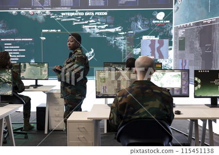Female master sergeant gathers battlefield intelligence reports on a big screen, creating new plans for secret war operations. Reconnaissance division ensuring national safety in army power base. 115451138