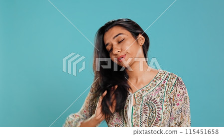 Portrait of cheerful friendly indian woman smiling, flipping long healthy hair, isolated over studio background. Happy brunette person confident with natural hairstyle, feeling satisfied, camera B Portrait of cheerful friendly indian woman smiling, flipping long healthy hair, isolated over studio background. Happy brunette person confident with natural hairstyle, feeling satisfied, camera B 115451658