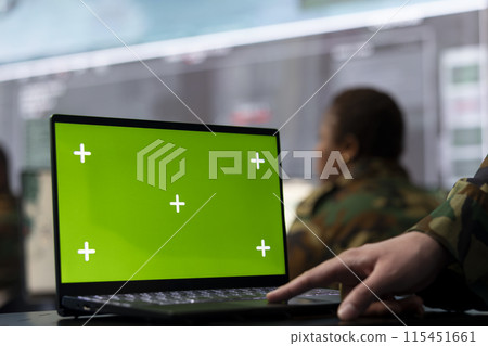 Trooper utilizing chroma key mockup screen on a laptop in military headquarters, providing real time data to ensure national safety. High ranking serviceman uses pc with copy space display. Trooper utilizing chroma key mockup screen on a laptop in military headquarters, providing real time data to ensure national safety. High ranking serviceman uses pc with copy space display. 115451661