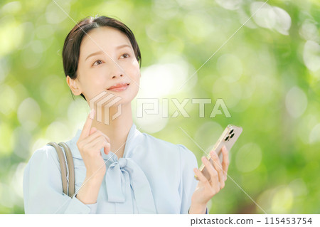 A woman holding a smartphone among the fresh greenery A woman holding a smartphone among the fresh greenery 115453754