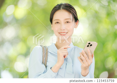 A woman holding a smartphone among the fresh greenery 115453759