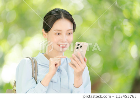A woman holding a smartphone among the fresh greenery A woman holding a smartphone among the fresh greenery 115453765