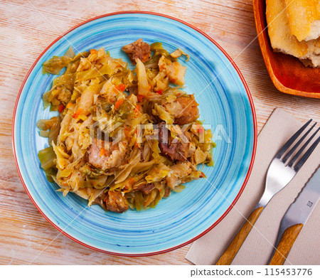 Appetizing cabbage stewed with pork meat on white plate 115453776