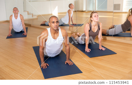 Sporty people practicing yoga training - pose bhujangasana Sporty people practicing yoga training - pose bhujangasana 115453941
