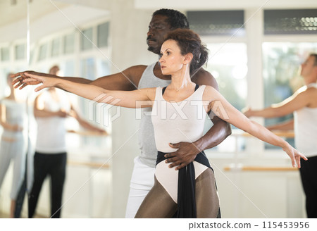 Rehearsing ballet movements in dance studio - man and woman performing adagio Rehearsing ballet movements in dance studio - man and woman performing adagio 115453956