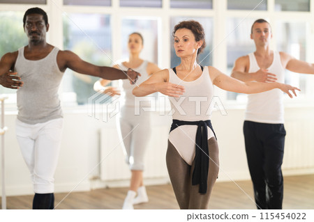 Fit woman practicing ballet movements at group class 115454022