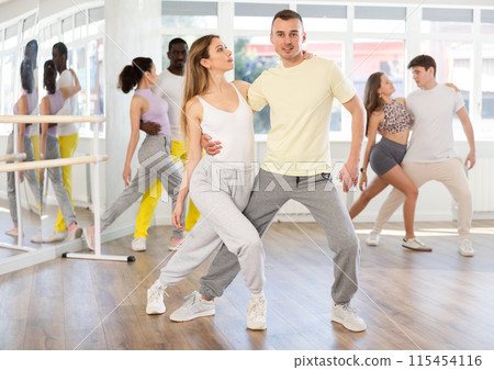 Pairs practicing Latino dance in training hall during dancing-classes. Pairs training ballroom dance 115454116