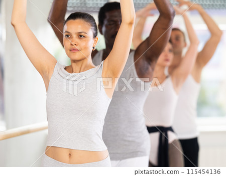 Group of dancers stand in fifth position at barre Group of dancers stand in fifth position at barre 115454136