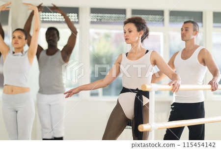 Woman and man dancers practicing batman tandu at barre 115454142