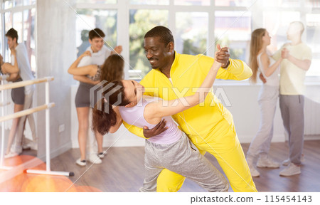 African American practicing bachata with brunette in dance class 115454143
