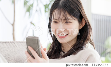 A woman looking at her smartphone in the living room 115454163
