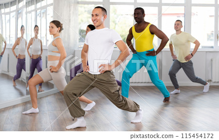 Young happy guy and international dancers preparing their modern dance at dance studio 115454172