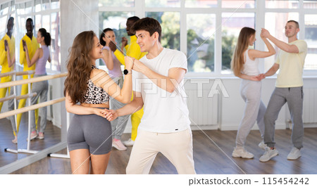 Young couple practicing passionate samba in dance class Young couple practicing passionate samba in dance class 115454242