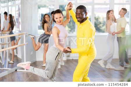 Couple male and girl rehearsing pair latino dance in studio Couple male and girl rehearsing pair latino dance in studio 115454284