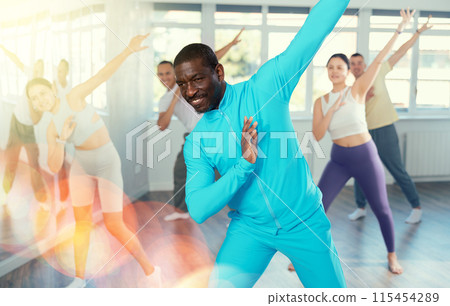African american man and group of young active sports people practicing rock and roll dance in dance hall 115454289