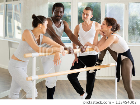 Group of dancers talking at ballet barre Group of dancers talking at ballet barre 115454302