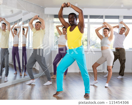 Enthusiastic black man energizing group during dance fitness class 115454306