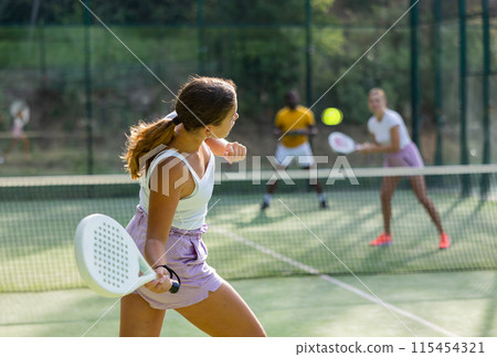 Sportive slim woman with racquet playing padel in court. View from back 115454321