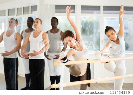 Ballet pose grand batman - ballet troupe of different nationalities at choreography lesson Ballet pose grand batman - ballet troupe of different nationalities at choreography lesson 115454329