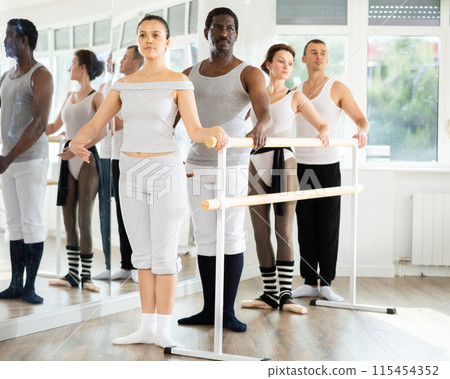 Group of ballet enthusiasts standing in first position at barre Group of ballet enthusiasts standing in first position at barre 115454352