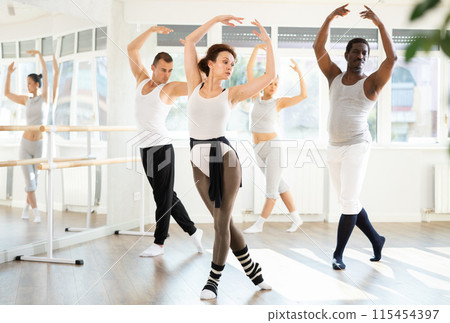 Graceful woman leading ballet class with adult amateur dancers Graceful woman leading ballet class with adult amateur dancers 115454397