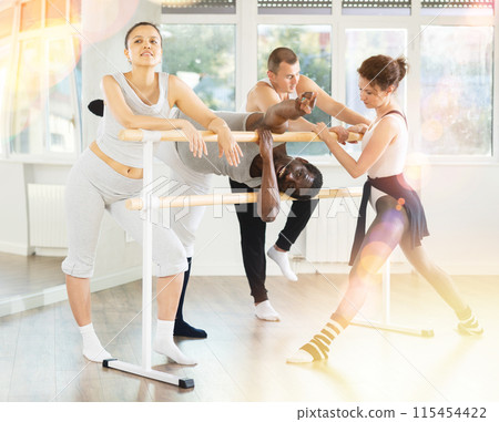 African American man goofing around by ballet barre with fellow dancers in studio 115454422