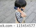 A child walking and using a smartphone 115454577