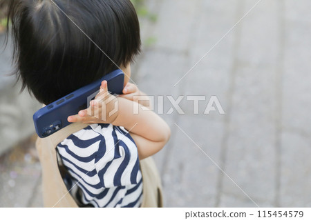 A child walking and using a smartphone 115454579