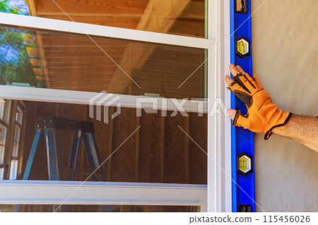 Installation of plastic windows in new residence by construction worker 115456026