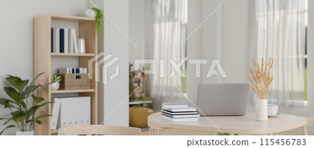 A laptop computer, books, and decor on a wooden table in a contemporary, minimalist living room. 115456783